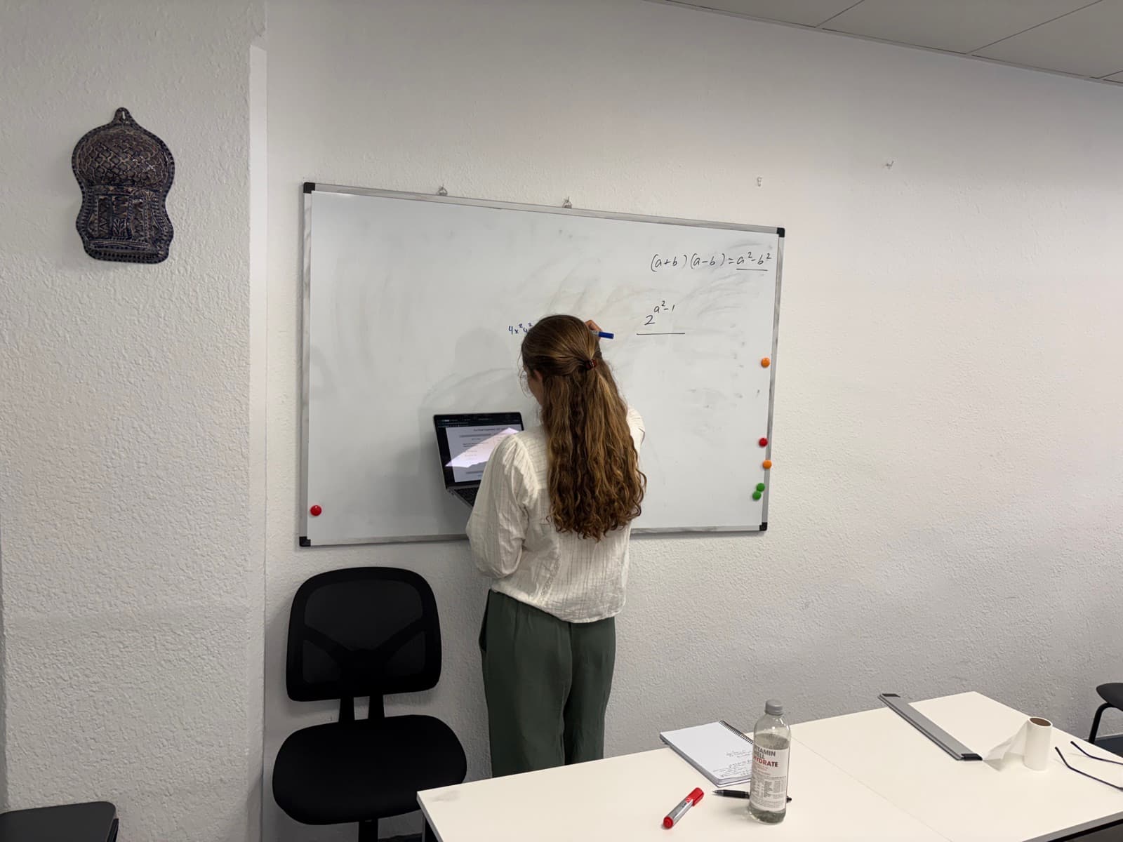 Student practising Digital SAT problems at the whiteboard alongside a laptop.